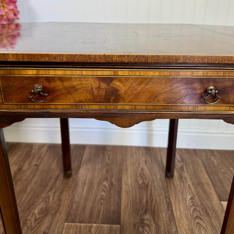 Close up of drawer front of federal side table showing band inlay, brass hardware, and flame mahogany grain pattern